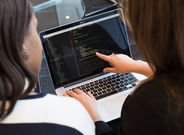 Dos personas revisan código en una laptop
